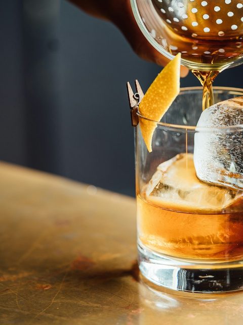 A cocktail being poured at a dimly lit bar.