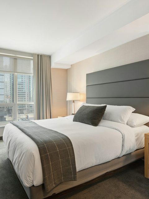 A softly lit hotel bedroom with crisp white bedding.