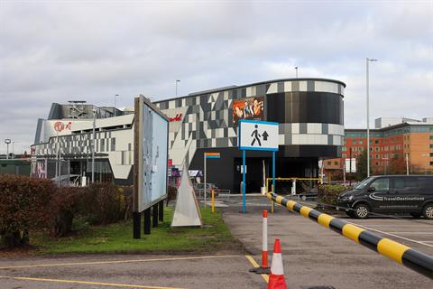 The patterned grey exterior of the Resorts World Birmingham car park, with the vehicle entrance and a pedestrian sign in front of it.