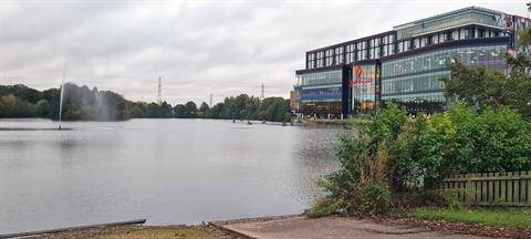 Pendigo Lake with a fountain playing, and the Resorts World Birmingham building standing on the far bank to the right.